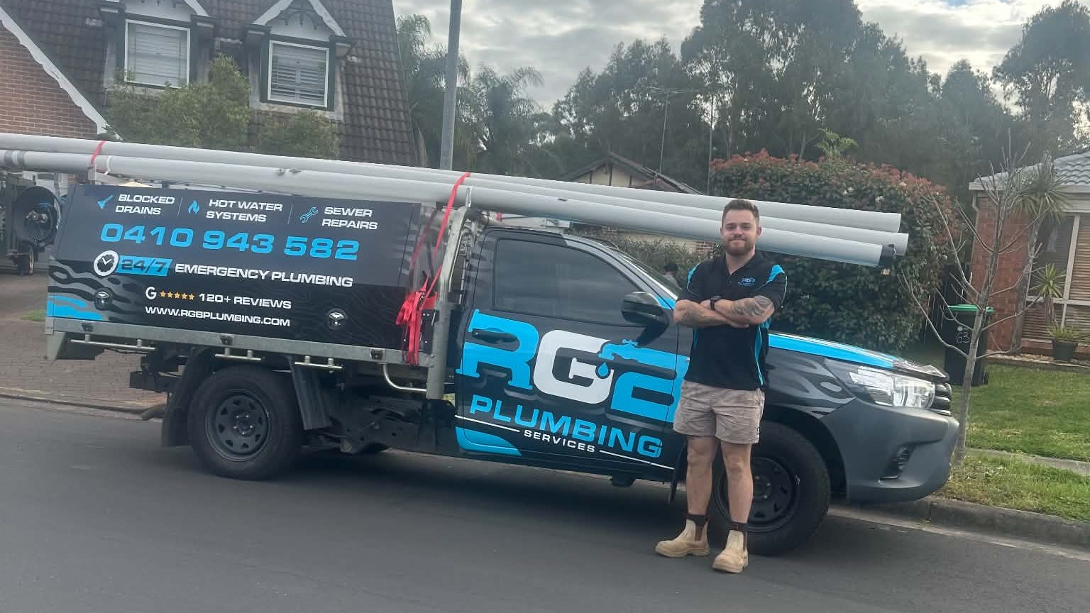 Rhys beside the branded RGB Plumbing vehicle